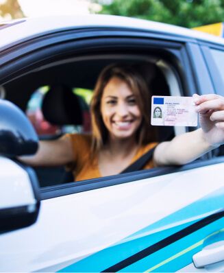 Eine Frau hält stolz ihren Führerschein in die Kamera